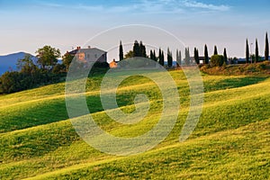 Magnificent spring landscape at sunrise.Beautiful view of typical tuscan farm house, green wave hills.