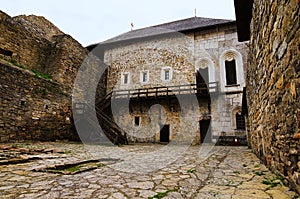 Magnificent view of courtyard with ancient stone building in the medieval castle. High stone wall with tower in the background.