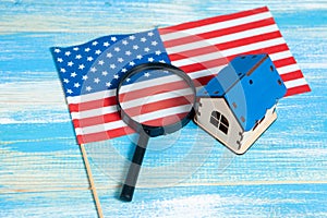 magnifier, American flag and house. home search concept. home inspection on a blue table