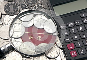 A magnifier and calculator with china yuan on the background of medical insurance bankbook