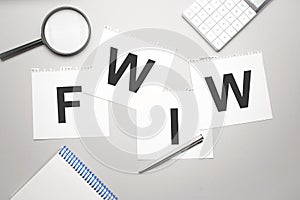 magnifier,calculator, pen and paper sheet with text fwiw