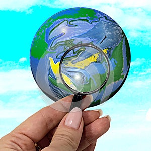 Magnifier in a female hand, enlarging the globe.