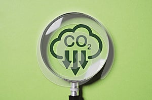 Magnifier glass with CO2 reduction on green background for decrease CO2 , carbon footprint and carbon credit to limit global