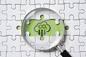 Magnifier glass with CO2 reduction on green background and jigsaw for decrease CO2 , carbon footprint and carbon credit to limit