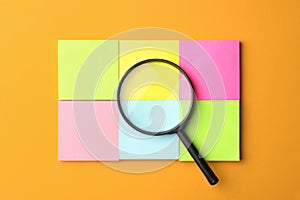 Magnifier glass and different memory stickers on orange background. Find keywords concept