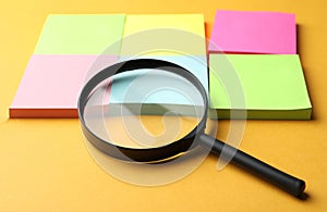 Magnifier glass and different memory stickers on orange background. Find keywords concept