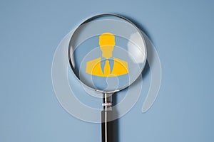 Magnifier glass focus to manager icon which is among staff icons for human resources, CRM, data mining and social media concept
