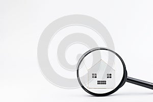 Magnifier glass in front of the model house isolated on white background.Real estate concept. Search and sale of housing. Rent a