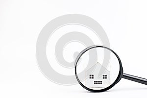 Magnifier glass in front of the model house isolated on white background.Real estate concept. Search and sale of housing. Rent a