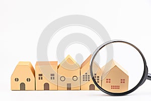 Magnifier glass in front of the model house isolated on white background.Real estate concept. Search and sale of housing. Rent a