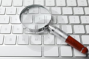 Magnifier glass on keyboard, closeup. Find keywords concept