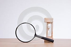 Magnifier with sandglass standing on desk