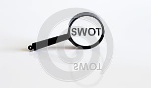 Magnifier with text SWOT on the white background