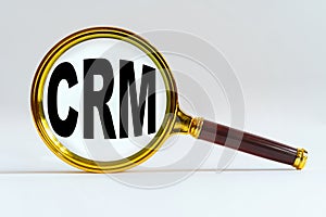 Magnifier on a white background, inside the text is written - CRM