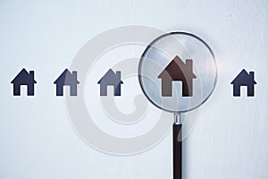 Magnifier zooming in on house icon on white background. Home and property search concept.