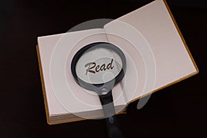 Magnifing glass on a book to help facilitate the vision for reading .