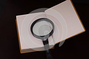 Magnifing glass on a book to help facilitate the vision for reading and to educate