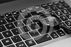 Magnifyer glass on laptop computer keyboard in black and white