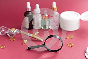 magnifying glass against the background of blurred face serums and dermoroller