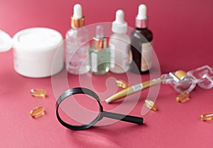 magnifying glass against the background of blurred face serums and dermoroller photo