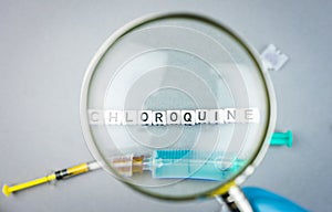 Magnifying glass on alphabet dices with the word Chloroquine a possible treatment for Corona Virus