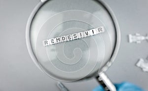 Magnifying glass on alphabet dices with the word Remdesivir a possible treatment for Corona Virus photo