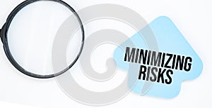 magnifying glass with blue arrow paper sheet with text minimizing risks