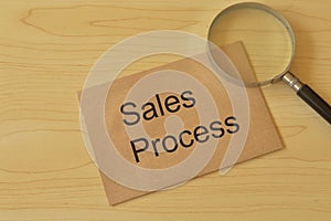 Magnifying glass and brown envelope with text SALES PROCESS