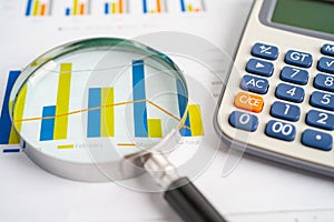 Magnifying glass and calculator on charts graphs paper. Financial development, Banking Account, Statistics, Investment Analytic