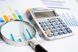 Magnifying glass and calculator on charts graphs paper. Financial development, Banking Account, Statistics, Investment Analytic