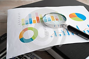 Magnifying glass and calculator on charts graphs paper. Financial development, Banking Account, Statistics, Investment Analytic