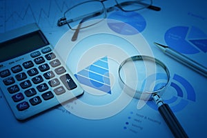 Magnifying glass, calculator, pen, and glasses on business budget graph, Financial research concept