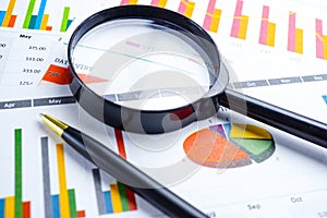 Magnifying glass on charts graphs spreadsheet paper. Financial development, Banking Account, Statistics.