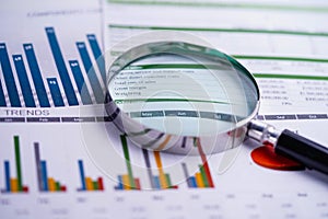 Magnifying glass on charts graphs spreadsheet paper. Financial development, Banking Account, Statistics, Investment Analytic.