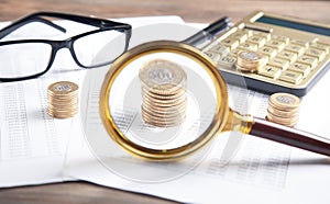 Magnifying glass, coins, eyeglasses, calculator, pen on financial documents. Business. Finance