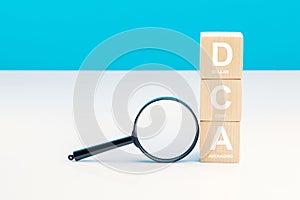 Magnifying glass and DCA word on a wooden cube in idea Dollar Cost Averaging investment strategy, Saving stock or savings on a