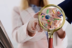 Magnifying glass detecting microbes and business partners shaking hands, closeup