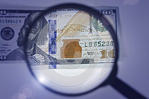 Magnifying glass on dollar banknotes. Hundred dollars banknote authentication. Inspecting a Hundred Dollar Bill