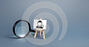 Magnifying glass and an easel with a new hired employee. Recruiting and HR management. Hiring new workers, staffing. Headhunters