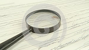Magnifying glass examining cursive script document detail