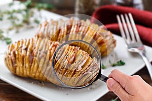 Magnifying glass examining hasselback potatoes