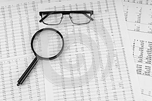 Magnifying glass and eye glasses on financial documents