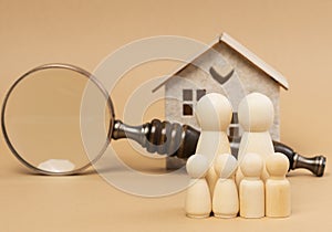 Magnifying glass and a family of wooden figures on the background of a house, the concept of searching for real estate rental