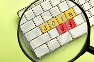 The magnifying glass focuses on the computer keyboard button with Join Us words