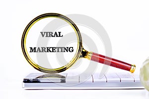 A magnifying glass focuses on the words viral marketing, highlighting its importance in today's technology-driven photo