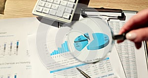 Magnifying glass focusing on chart and financial report in charts