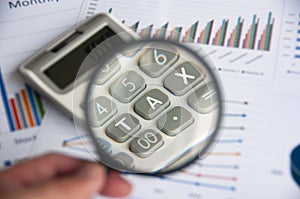 Magnifying glass focusing on TAX work on calculator. Business and tax concept.