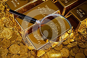 Magnifying glass with gold bar pile of gold coins