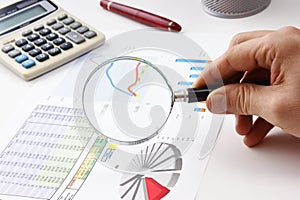 Magnifying glass in hand and working paper