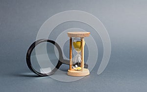 Magnifying glass and hourglass. Search for time and resources. Streamline business, increase efficiency and reduce downtime photo